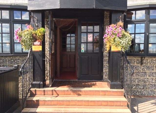 The side entrance has hanging baskets either side of the steps